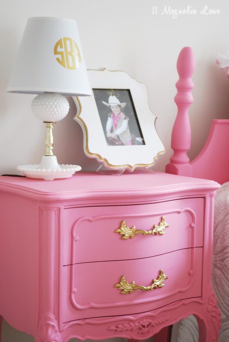 a cute girl's room with pink furniture and gold accents