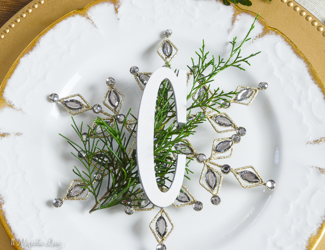 Holiday table with gold, white, evergreen, snowflakes, and rocking horse | 11 Magnolia Lane