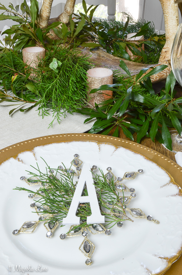Holiday table with gold, white, evergreen, snowflakes, and rocking horse | 11 Magnolia Lane